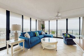 A spacious balcony with a blue sofa, a round white table, and a chair. - Sea Colony 6th floor condo w/ balcony, shared tennis court & partial ocean view (Bethany Beach)
