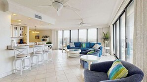 A spacious living area with a sofa, chairs, a coffee table, and a ceiling fan. - Sea Colony 6th floor condo w/ balcony, shared tennis court & partial ocean view (Bethany Beach)