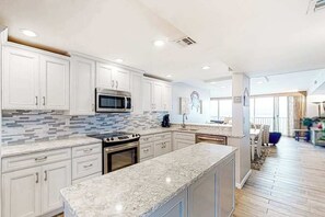 A modern kitchen with white cabinets, a granite countertop, stainless steel appliances, and a tiled backsplash. - Sea Colony Ocean 14th floor condo with elevator, WiFi, and basketball court (Bethany Beach)