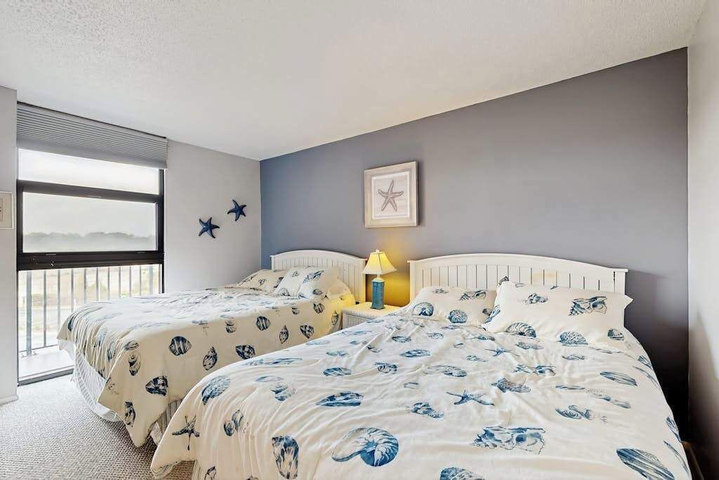 Un dormitorio con dos camas, una ventana y una decoración de estrella de mar en la pared.