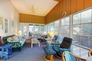 A spacious room with a large window, a ceiling fan, and a variety of seating options including a sofa, chairs, and a small table. - Sea Del Estates Home with Outdoor Shower, Grill, & Community Beach & Tennis (Bethany Beach)