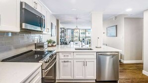 A modern kitchen with white cabinetry, a stainless steel refrigerator, and a built-in oven. - Sea Colony 1st floor condo w/ tennis court, shared sauna & balcony w/ ocean view (Bethany Beach)