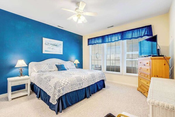 A bedroom with a bed, nightstand, dresser, and window with blinds.