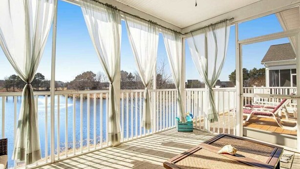 Una terrazza coperta con vista su un lago, un tavolo con una conchiglia e poltrone da relax.