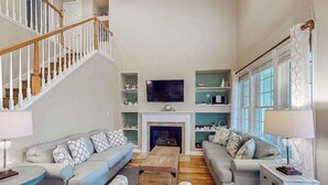 Ein Wohnzimmer mit Treppe, Kamin und Fernseher.