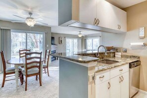 A kitchen with a central island, overhead cabinets, and a dining area with chairs. - Sea Colony Tennis 1st floor condo w/ pool, shared sauna, and lake view (Bethany Beach)