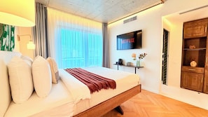 Habitación de hotel con una cama, un televisor montado en la pared y un armario de madera.