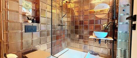 Un baño moderno con cabina de ducha de vidrio, inodoro y lavamanos.