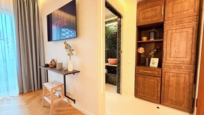 A room with a wooden cabinet, a small table with a vase, and a wall-mounted TV displaying 'NETFLIX'. - Modern Studios Steps from Piața Romană (Bucharest)