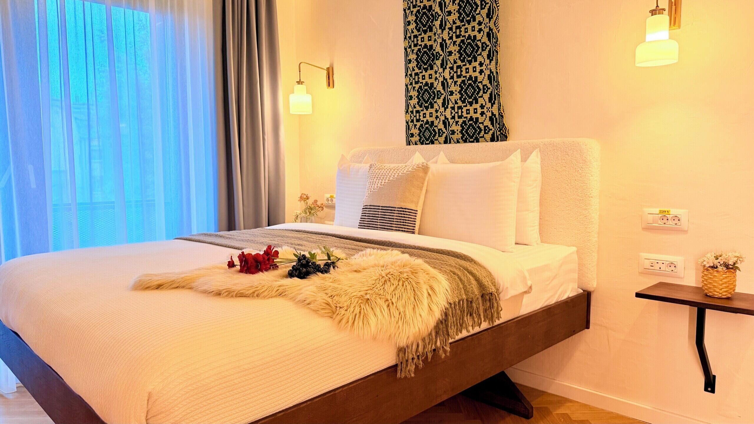 Una cama con un edredón mullido, una almohada decorativa y una mesita de noche con una planta.