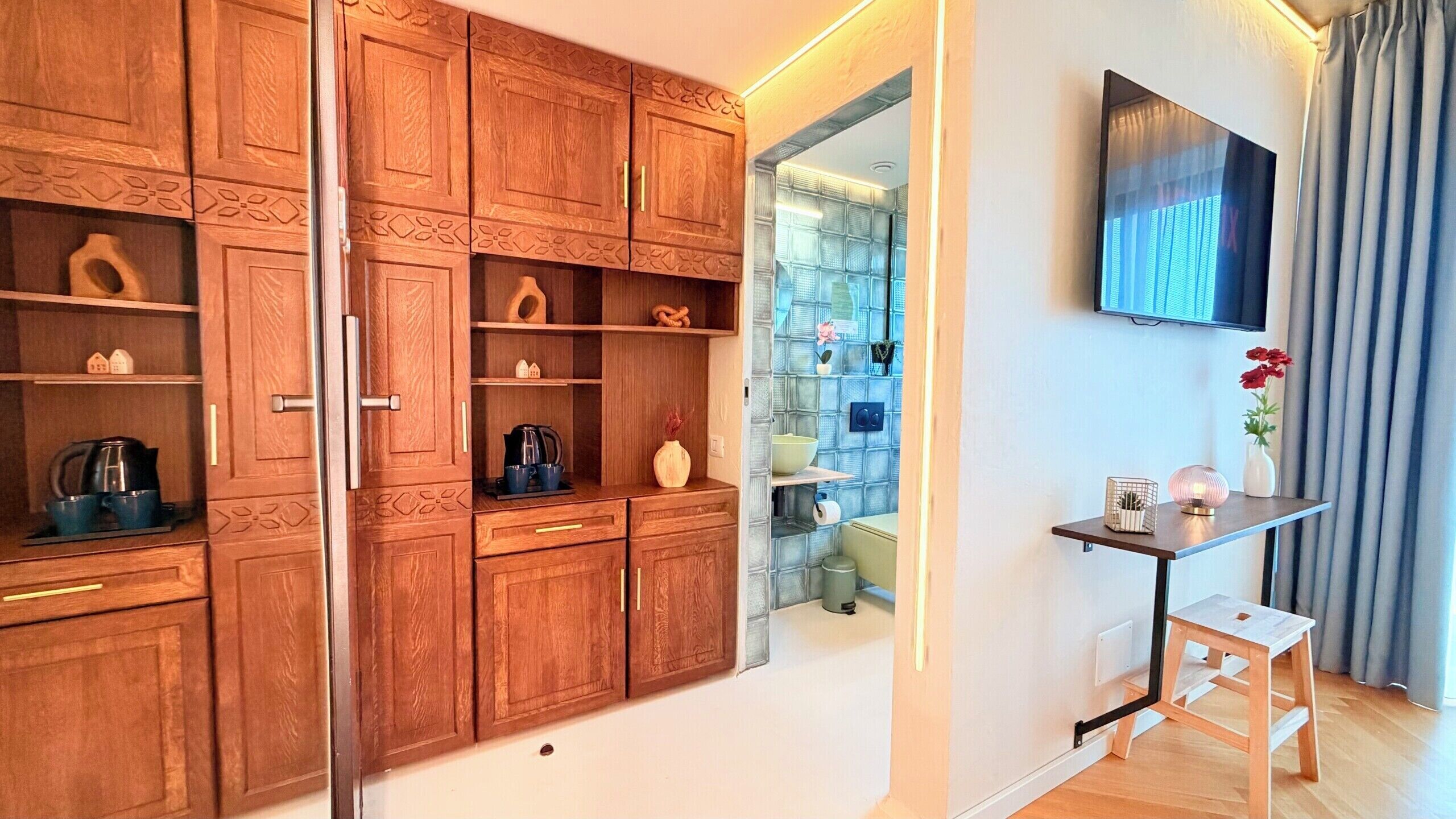 Une cuisine moderne avec des meubles en bois, un four encastré et un petit coin repas comprenant une table et une chaise.