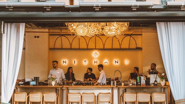 A bar area with a chandelier, a counter with staff, and a seating area with tables and chairs. - Modern Studios Steps from Piața Romană (Bucharest)