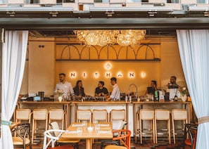 A bar area with a chandelier, a counter with staff, and a seating area with tables and chairs. - Modern Studios Steps from Piața Romană (Bucharest)