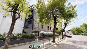 A modern building with a checkered facade, outdoor seating, and trees along the sidewalk. - Modern Studios Steps from Piața Romană (Bucharest)