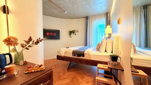 A modern hotel room with a bed, a desk, a chair, a TV displaying 'NETFLIX', and a window with curtains. - Modern Studios Steps from Piața Romană (Bucharest)
