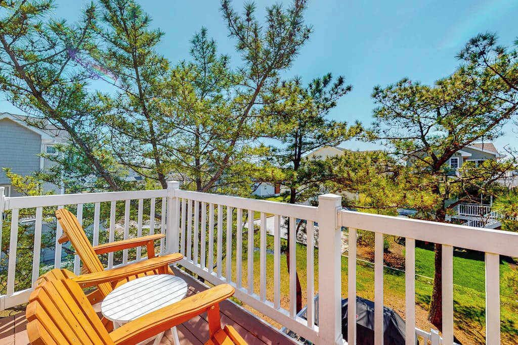 A wooden deck with a white railing, a single wooden chair, and a small table.