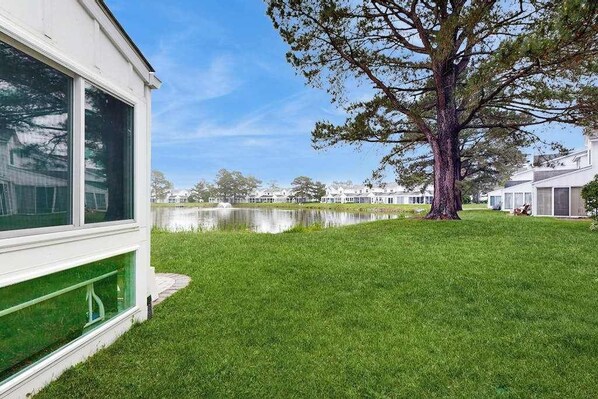A residential area with a large tree, a body of water, and houses in the background. - Mallard Lakes Waterfront Getaway w/ Free WiFi, A/C, Shared Pools, & Hot Tub (Selbyville)