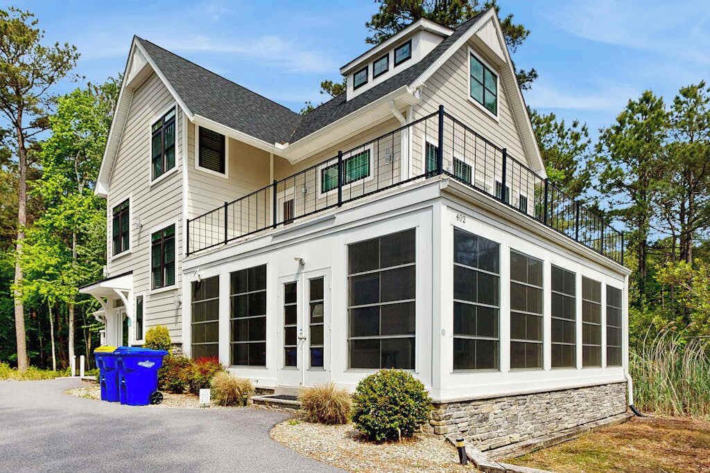 A two-story house with a large bay window, a stone foundation, and a garage.