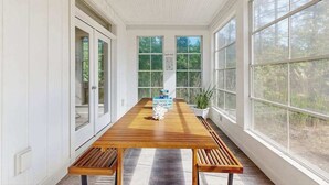Une longue table en bois, avec des bancs, de grandes fenêtres et une plante en pot.