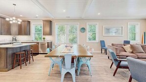 Une cuisine spacieuse dotée d’un îlot central, d’un coin repas avec des chaises et d’un salon avec un canapé et des fauteuils.