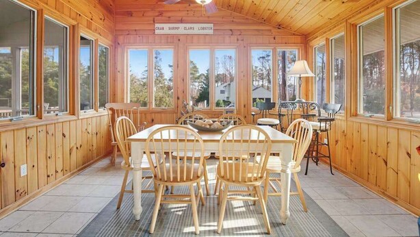 A wooden cabin with a dining area featuring a table and chairs, large windows, and a ceiling fan. - Town of Bethany Beach Home Near Fun Activities & Adventures w/Free WiFi & WD (Bethany Beach)