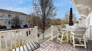 Um terraço com área de estar ao ar livre, guarda-corpo e vista para um edifício ao fundo.