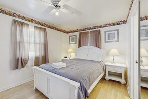 A bedroom with a bed, nightstands, a ceiling fan, and curtains. - Fenwick Island Condo on 2nd Floor w/Free WiFi, Washer/Dryer, Central AC, & Cable (Fenwick Island)