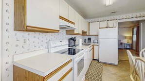 Eine Küche mit weißen Schränken, einem Herd, einer Spüle und einem Kühlschrank.