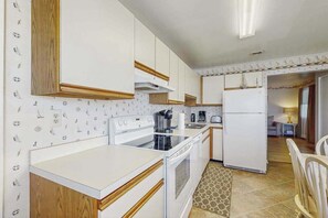 A kitchen with white cabinets, a stove, a sink, and a refrigerator. - Fenwick Island Condo on 2nd Floor w/Free WiFi, Washer/Dryer, Central AC, & Cable (Fenwick Island)