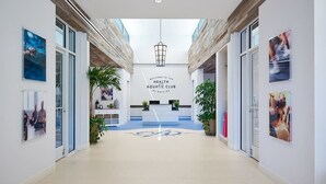 A modern lobby with a reception desk, a sign reading 'Welcome to the Health Aquatic Club,' and a central light fixture. - Updated Bayside Resort Home w/ Shared Pools, Easy Beach Access, & Fast WiFi (Selbyville)