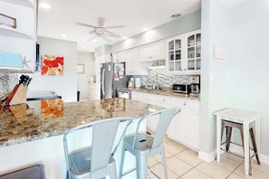 A kitchen with white cabinets, a granite countertop, and a ceiling fan. - Town of Bethany Beach oceanfront home with pool & tennis access, washer/dryer (Bethany Beach)