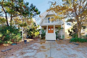 A two-story house with a front porch, a small balcony, and a gravel driveway. - Town of Bethany Beach oceanfront home with pool & tennis access, washer/dryer (Bethany Beach)