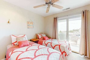 Ein Schlafzimmer mit zwei Betten, einem Deckenventilator, einem Fenster mit Vorhängen und einem Schild an der Wand.