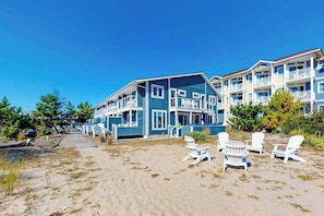 A beachfront hotel with multiple-story buildings, outdoor seating, and a sandy walkway. - Sandywalk Townhouse Right on the Beach with Free WiFi, Private Washer/Dryer (Bethany Beach)