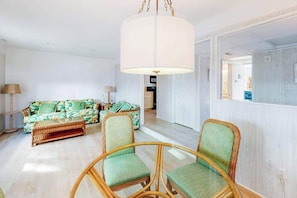 A room with a sofa, two chairs, a hanging light fixture, and a view into another room. - Sandywalk Townhouse Right on the Beach with Free WiFi, Private Washer/Dryer (Bethany Beach)