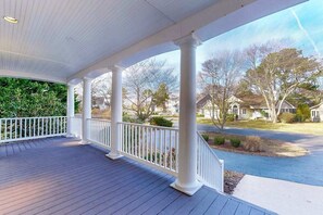 A covered porch with white railings and columns, a wooden deck, and a view of a residential street. - Salt Pond House close to beach with W/D, pool, tennis access (Bethany Beach)