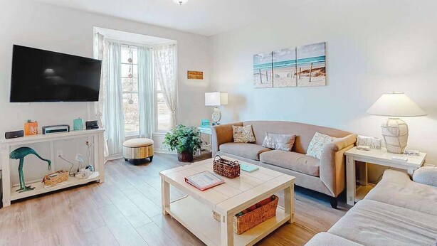 Ein Wohnzimmer mit Flachbildfernseher, einer Couch, einem Couchtisch und einer Lampe.