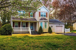 A two-story house with a front porch, a garage, and a well-maintained lawn. - Cottages on Whites Creek house near beach w/private W/D, shared pool, free WiFi (Ocean View)