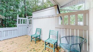 Une véranda couverte avec un plancher en bois, des balustrades blanches et deux chaises.