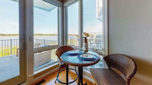Een balkon met een glazen tafel, rieten stoelen en een vaas met bloemen.