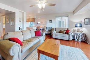 A living room with a sofa, armchair, and coffee table, a ceiling fan, and a dining area with chairs and a table. - Stewards Watch ownhouse close to the ccean w/shared pool, free WiFi, private W/D (Bethany Beach)