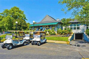 Un bâtiment doté d’un auvent vert, d’un porche abrité et d’un espace de stationnement pour les voiturettes de golf.