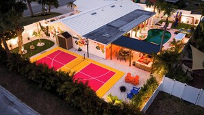 A residential property with a basketball court, outdoor seating area, and a swimming pool. - Hippie House-5 bedroom, Sleeps 12! Pool, Basketball, Mini golf, Pickleball Ct! (Bradenton)