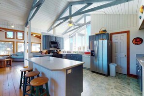 A spacious kitchen with a large island, bar stools, and a ceiling fan. - Ocean Village Home Steps From Beach w/Free WiFi + Private Washer and Dryer (Bethany Beach)
