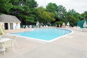 A rectangular pool with a tiled deck, lounge chairs, and umbrellas. - Bayberry Woods condo with fast WiFi, on-site pool, tennis & pickleball (Bethany Beach)