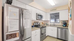 A modern kitchen with stainless steel appliances, white cabinetry, and a window with blinds. - Sea Pines Village Beach House with Fast WiFi, Full Kitchen, A/C, & a Shared Pool (Bethany Beach)