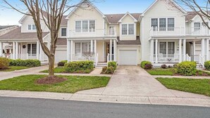 A row of two-story houses with front porches, a driveway, and a tree in the foreground. - Bear Trap Dunes townhome with central AC & washer/dryer - on-site pools & tennis (Ocean View)