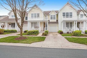 A row of two-story houses with front porches, a driveway, and a tree in the foreground. - Bear Trap Dunes townhome with central AC & washer/dryer - on-site pools & tennis (Ocean View)