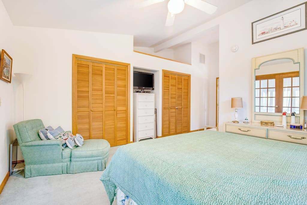 A bedroom with a bed, a sofa, a dresser, and wooden closets.