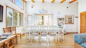 A dining area with a table and chairs, a bookshelf, and a window with blinds. - Fenwick Island spacious beach house with deck, W/D & full kitchen - dog-friendly (Fenwick Island)